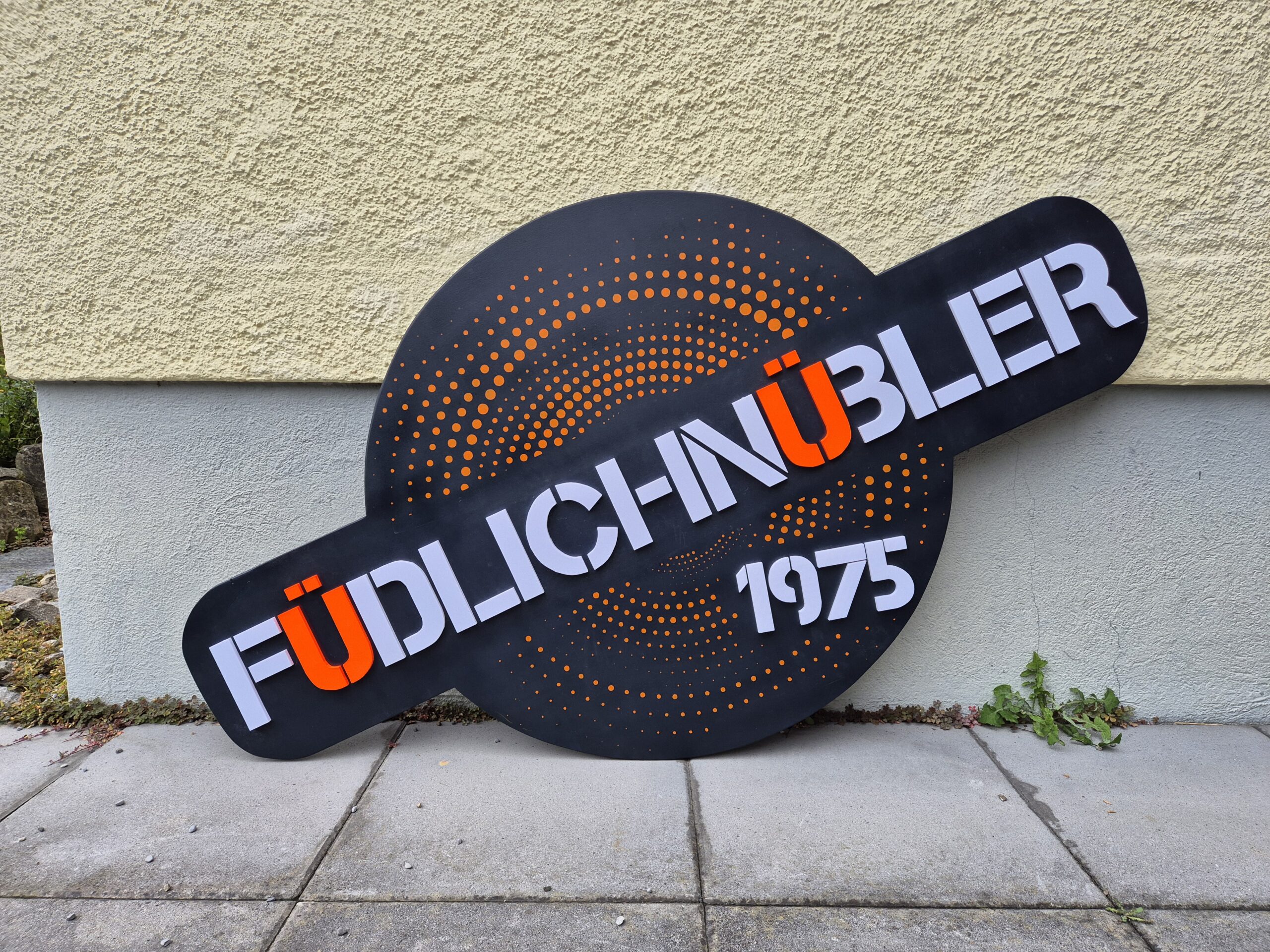 Fertige Holztafel von gmaled.ch: schwarzer Grund mit orangen Punktmustern und weissen Buchstaben