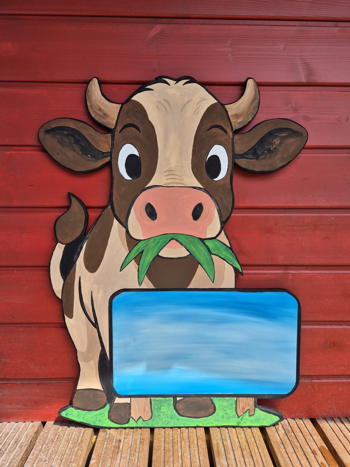 Kuh mit Gras im Maul und blauer Namensfläche