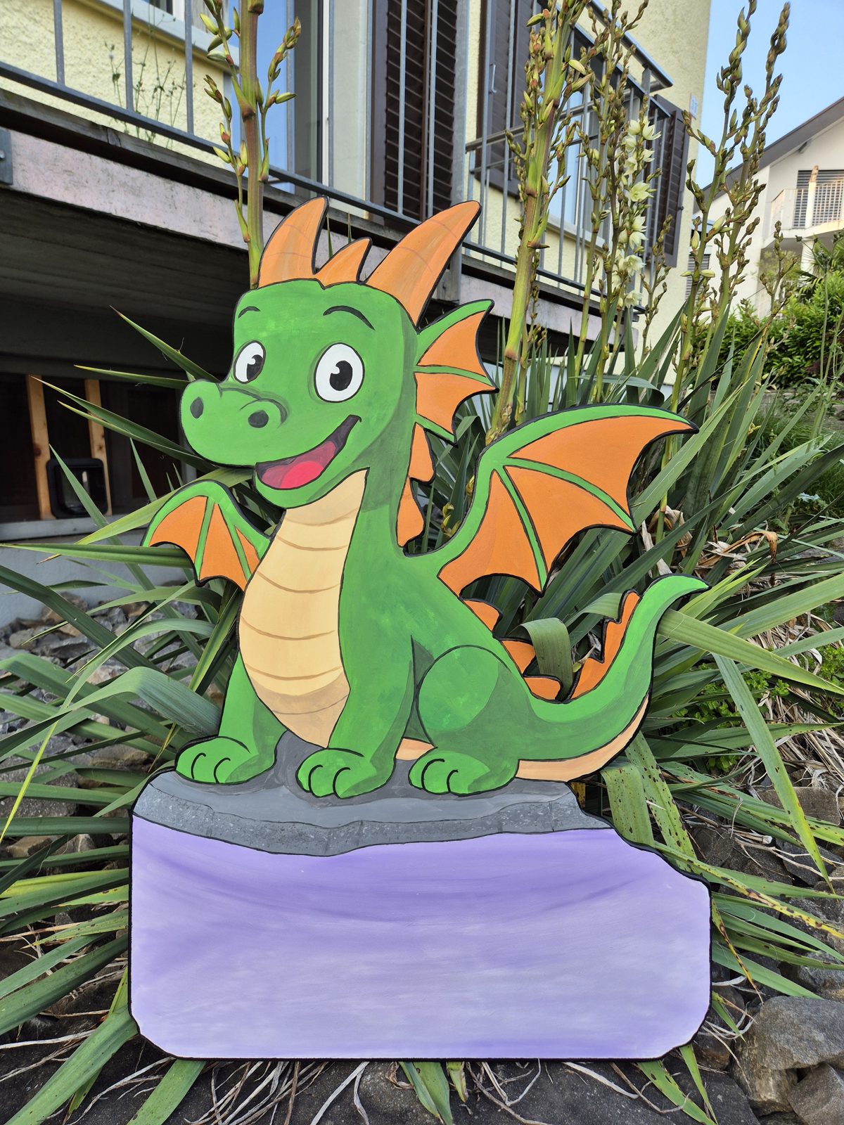 Grüner Drache auf einem Stein mit violetter Namensfläche