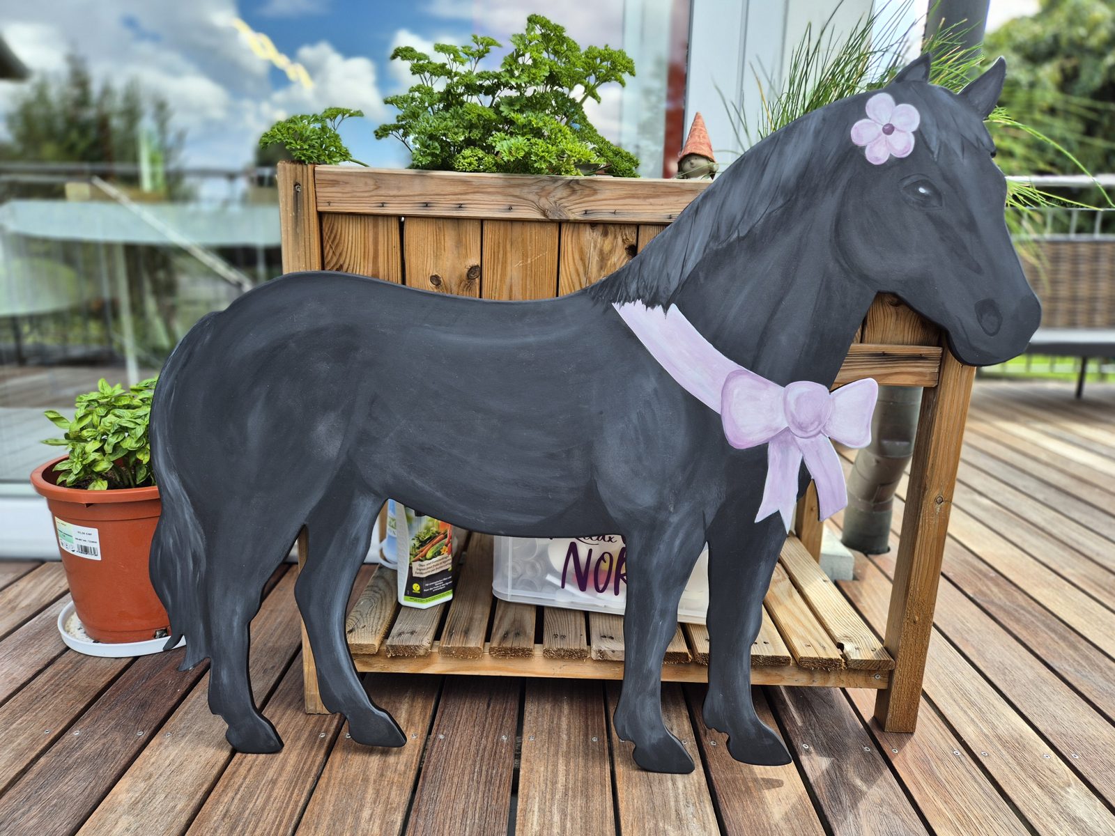 Dunkles Pony mit rosa Schleife und Blume
