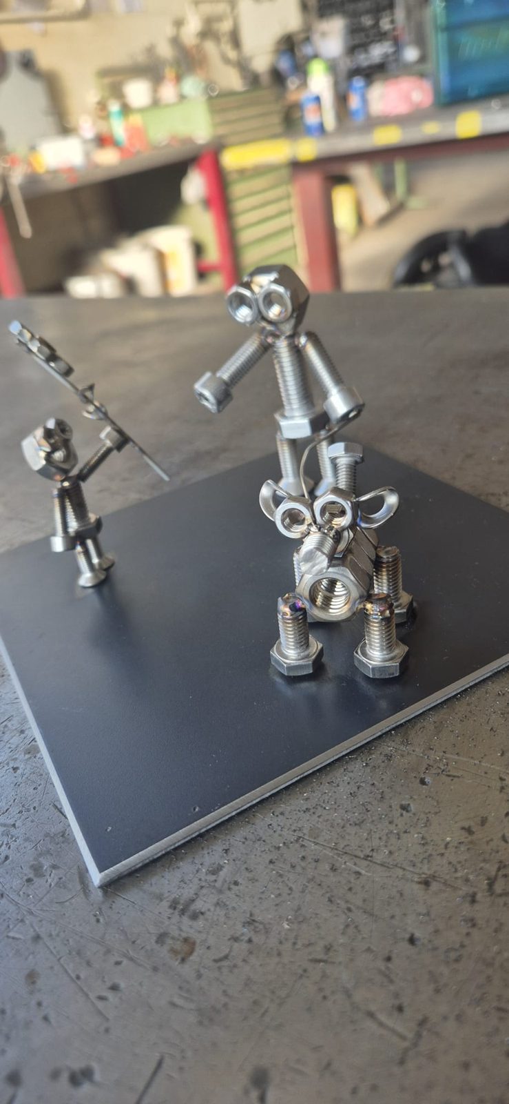 Zwei kleine Metallfiguren und ein Metalltier auf einer Stahlplatte