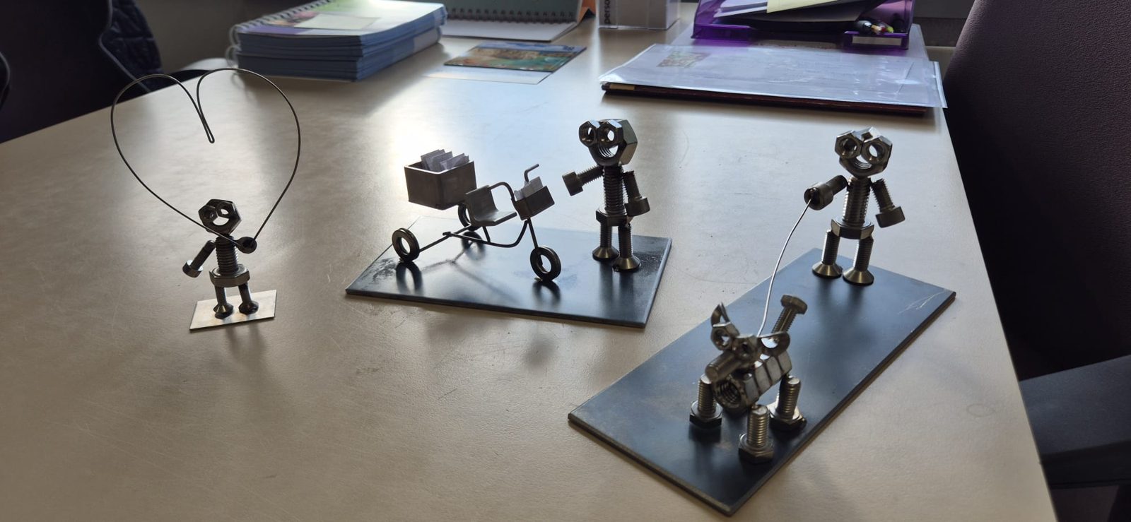 Mehrere Metallfiguren auf einem Tisch, darunter ein Männchen mit Karre und eines mit Hund