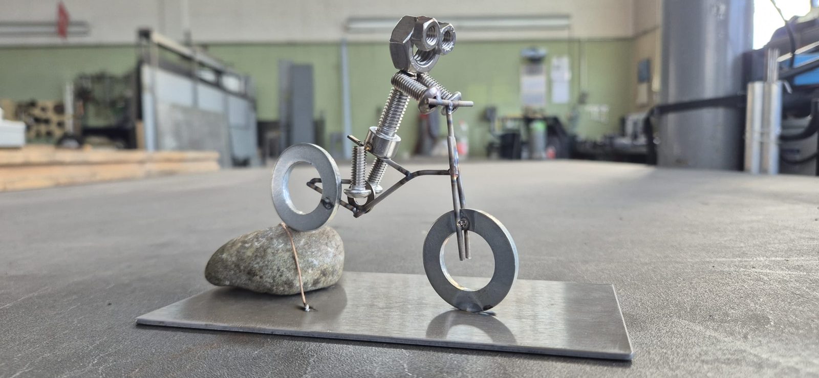 Metallmännchen fährt Fahrrad über einen Stein
