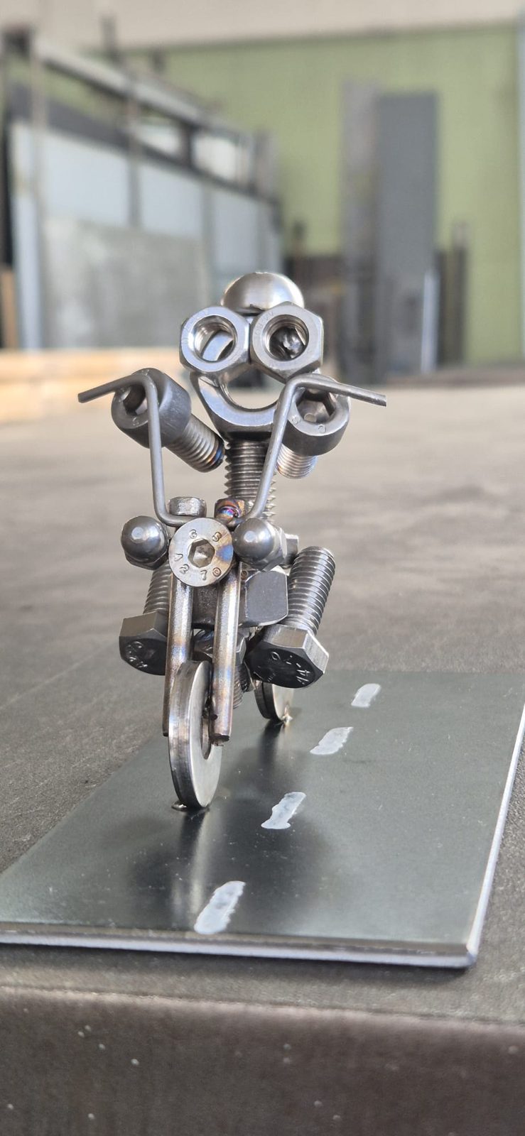 Metallmännchen auf einem Motorrad auf einer Platte mit Strassenmarkierung