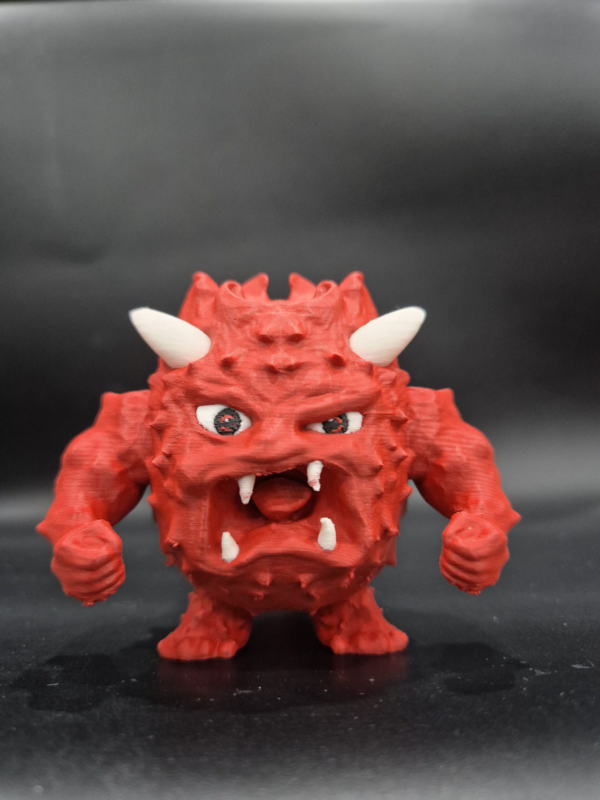Rote Monsterfigur mit weissen Hörnern und Zähnen
