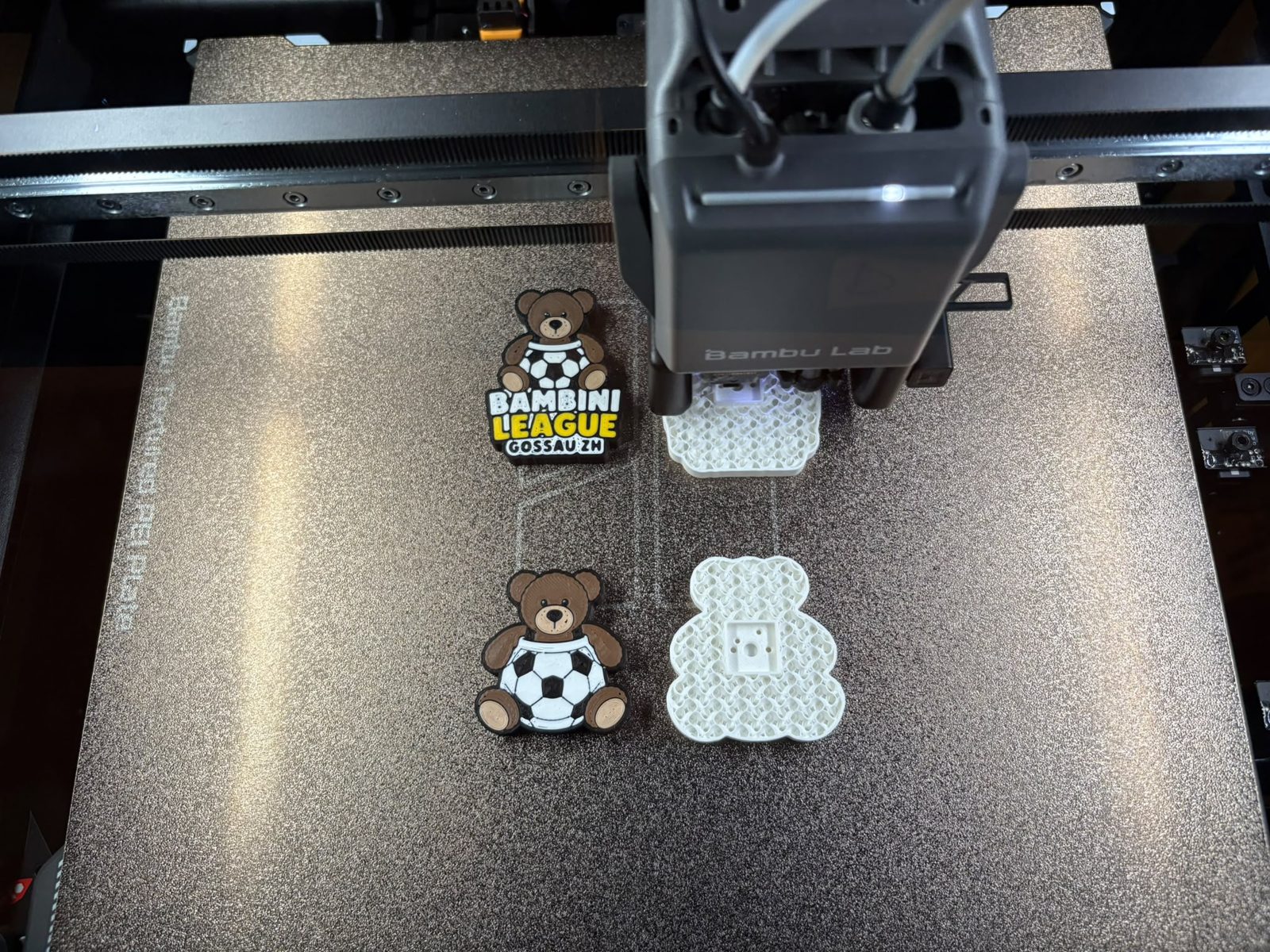 Ein 3D-Drucker druckt Bären-Figuren, daneben ein fertiger Bär mit Fussball