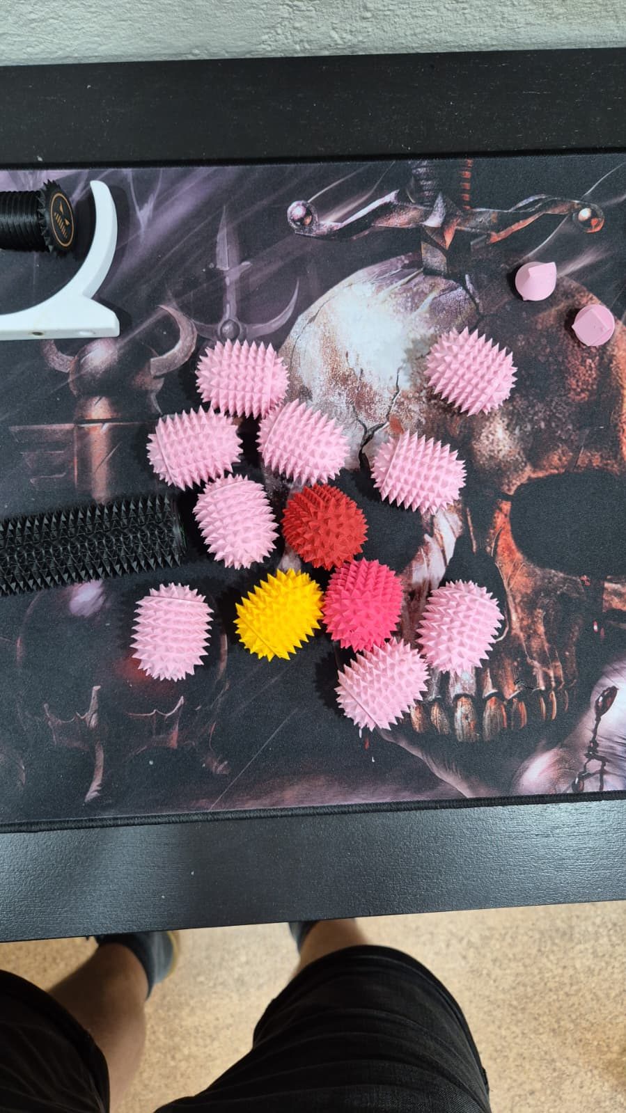 Rosa, rote und gelbe Stachelbälle aus dem 3D-Drucker auf einer Unterlage